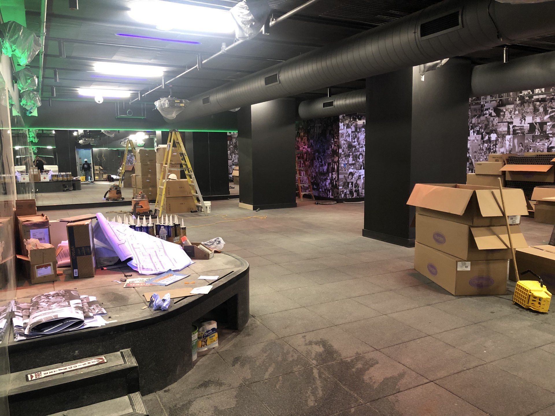 Studio renovation in progress with ladders, boxes, and unfinished flooring