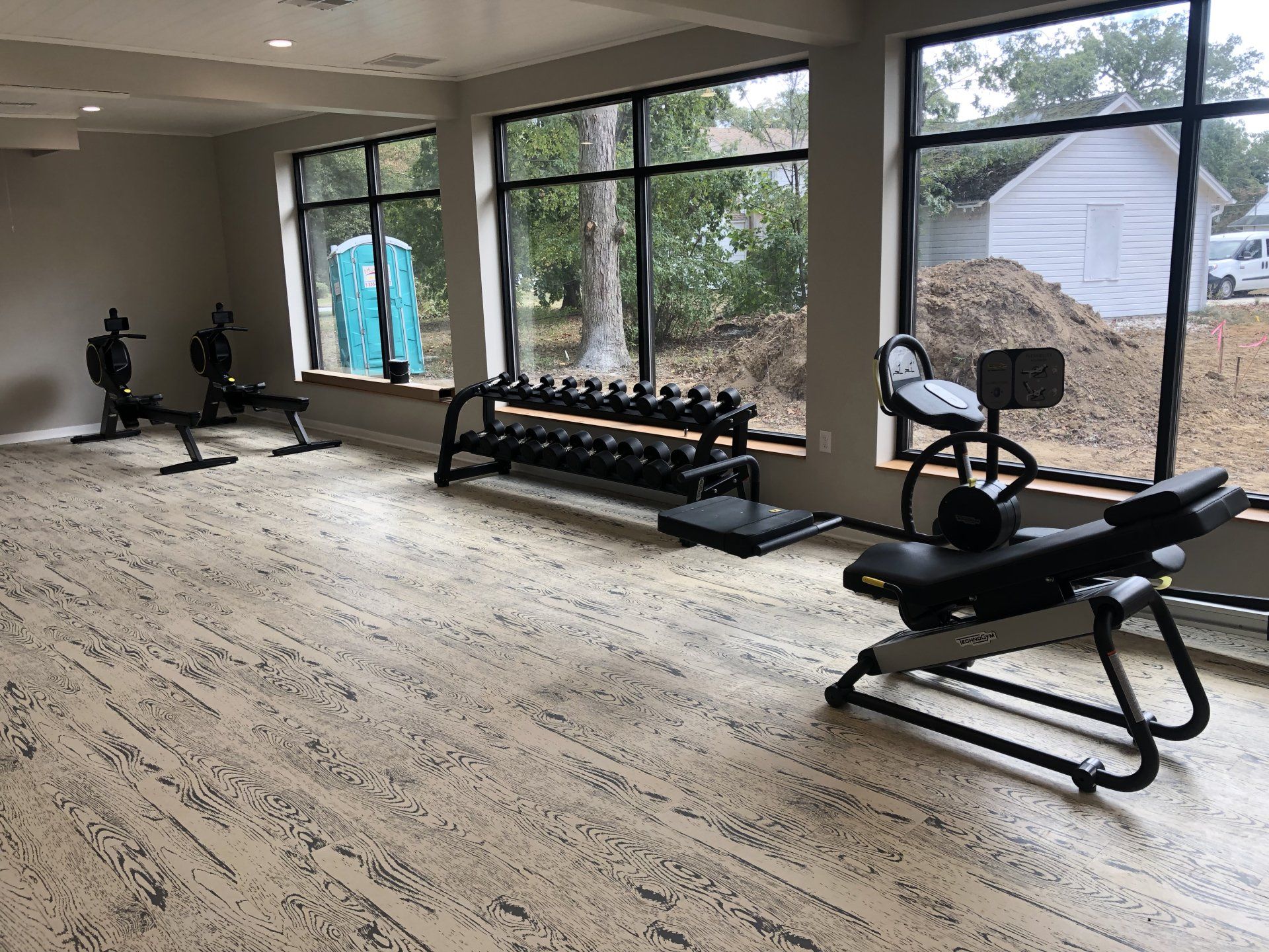 Weight benches and dumbbells by large windows at Daily Fitness