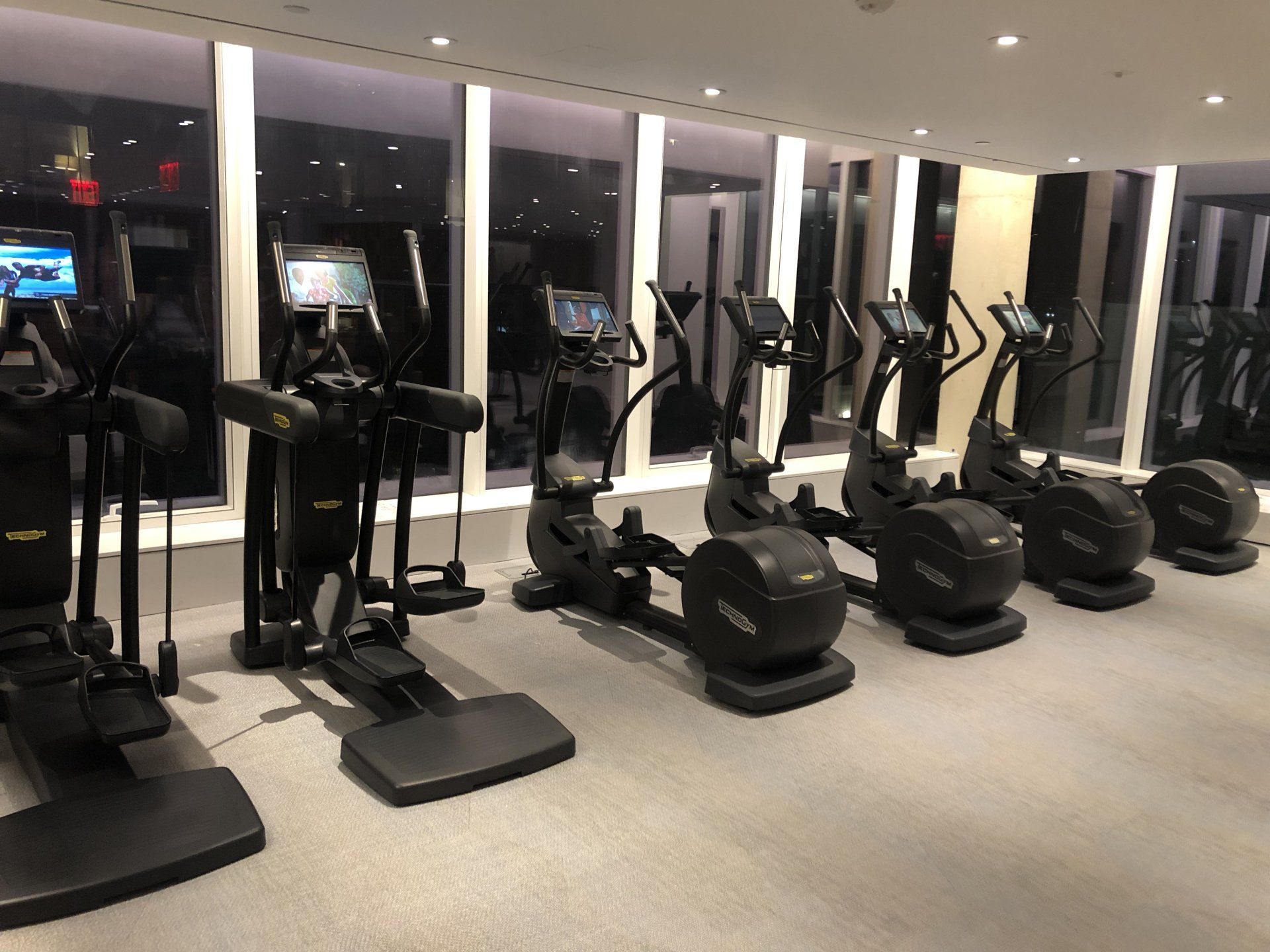 Row of elliptical machines with waterfront views in apartment gym.