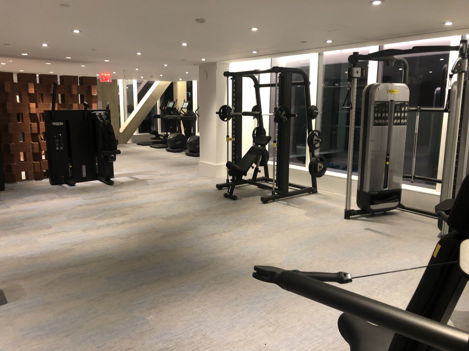 Modern apartment fitness room with strength training machines and open space.