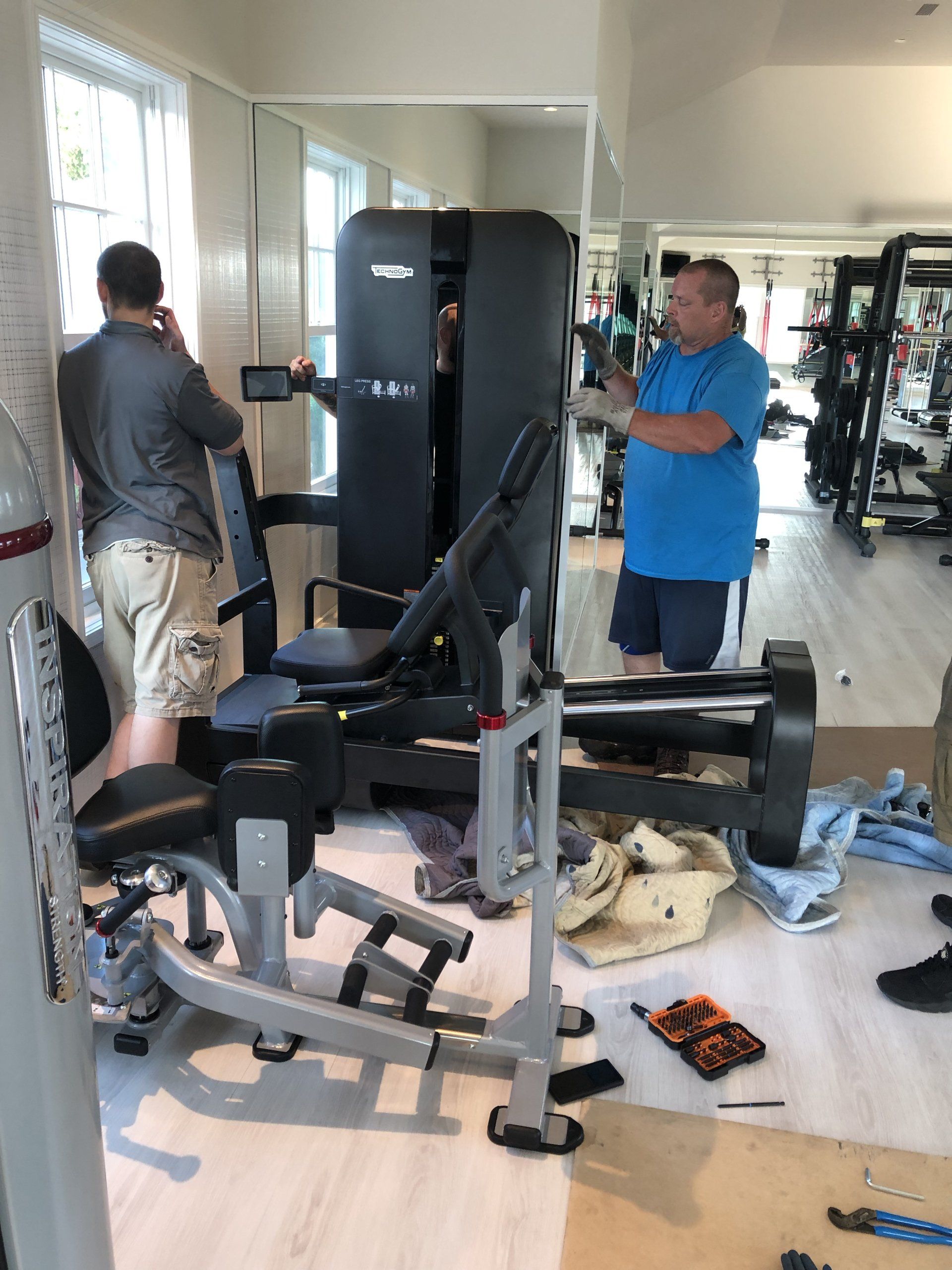 Workers installing strength training equipment in a residential gym.