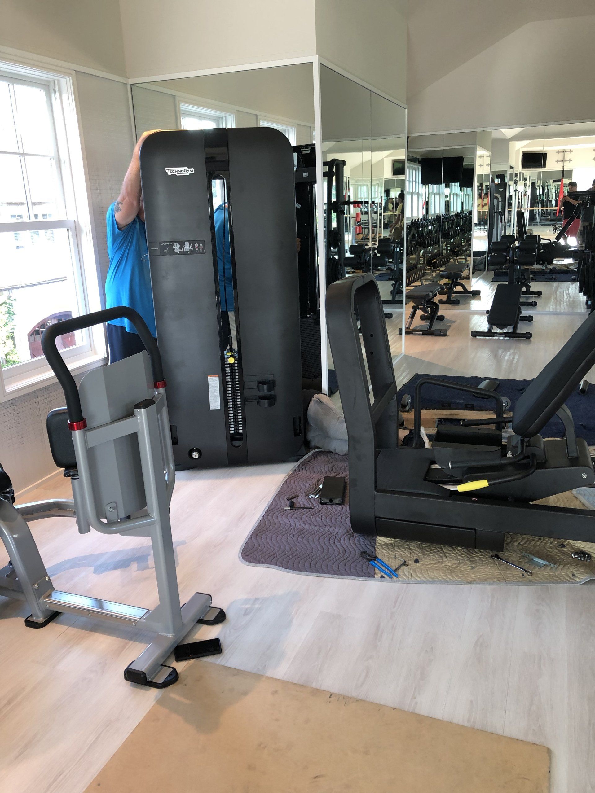 Residential gym with weight machines set up near large windows.