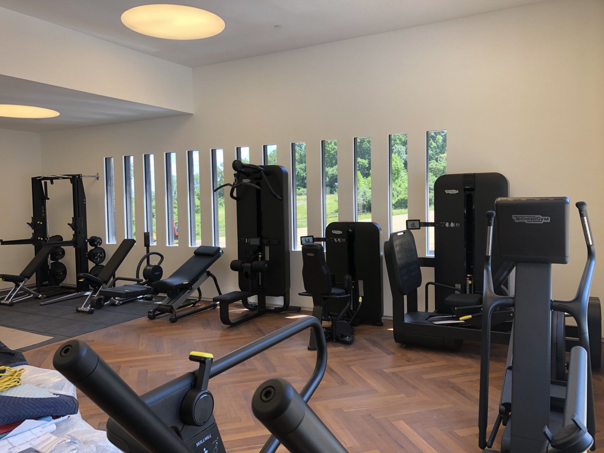 Completed Bernardsville home gym featuring multiple strength and cardio training machines.