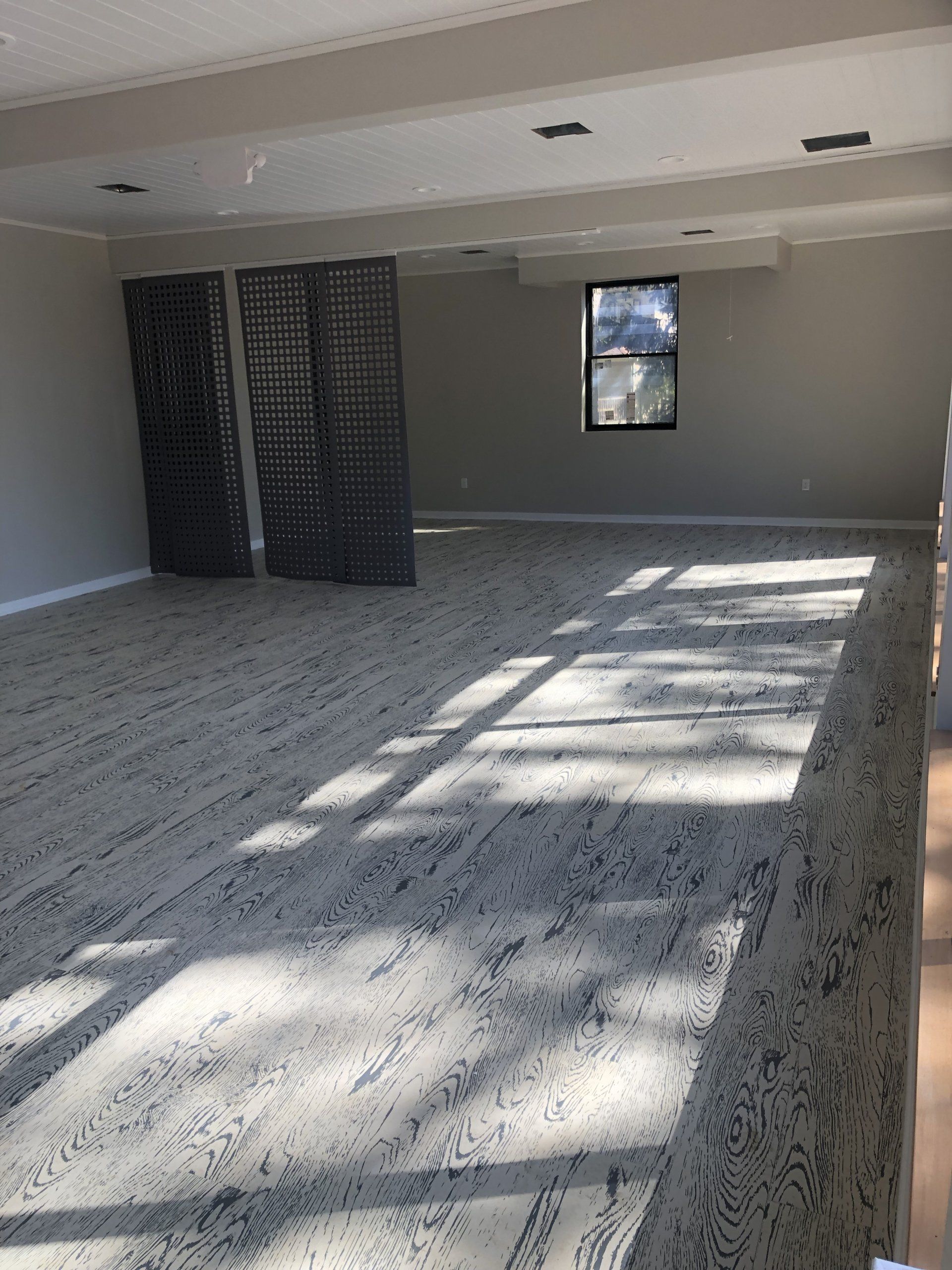 Sunlit fitness studio with patterned floors and wall mirrors at Daily Fitness.