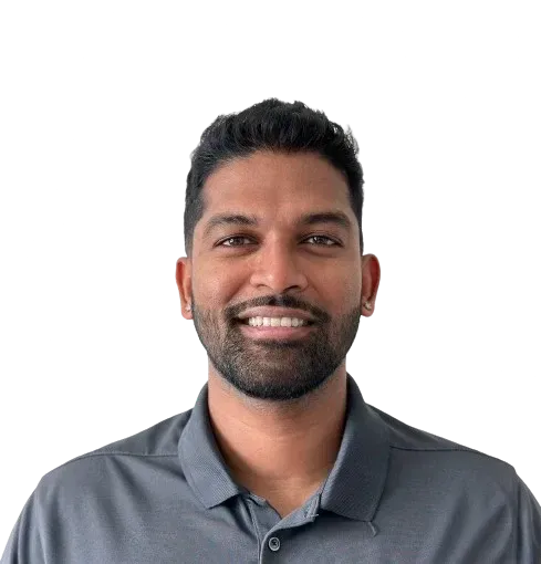 A man with a beard is smiling for the camera while wearing a grey shirt.