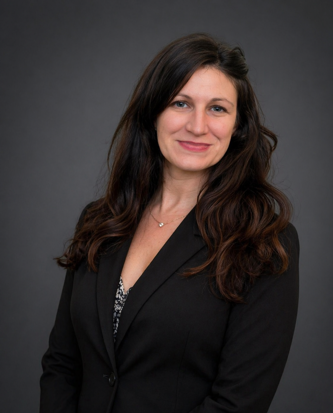 Woman in a blue blazer smiles, long dark hair.