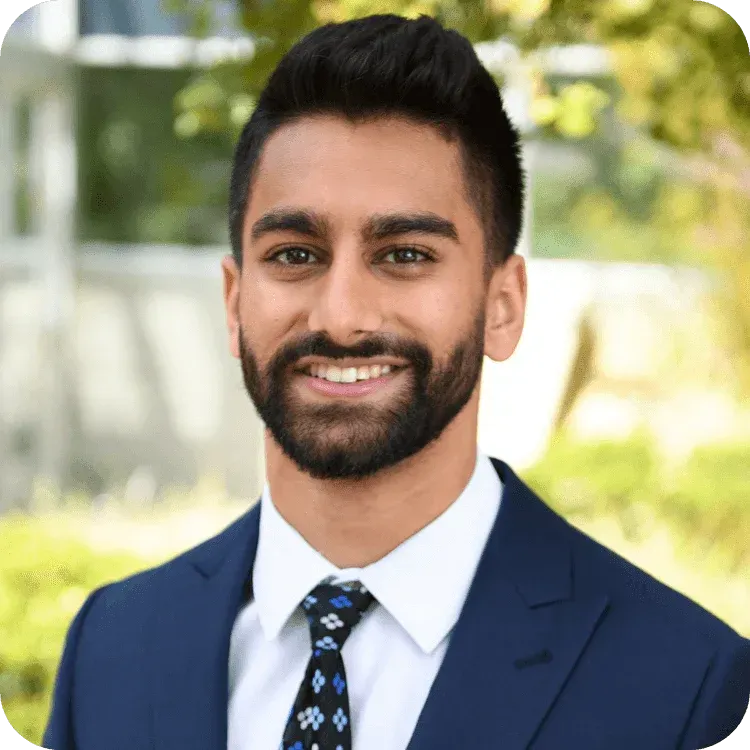 A man with a beard is wearing a suit and tie and smiling.