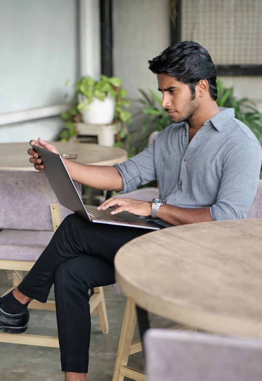 A man is sitting at a table using a laptop computer.