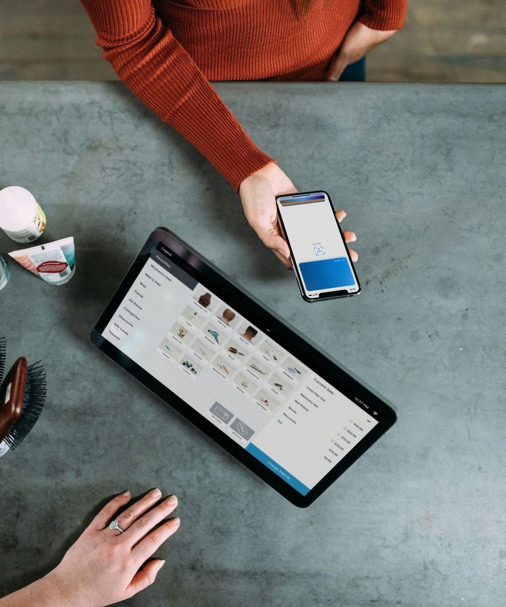 A woman is holding a cell phone next to a tablet
