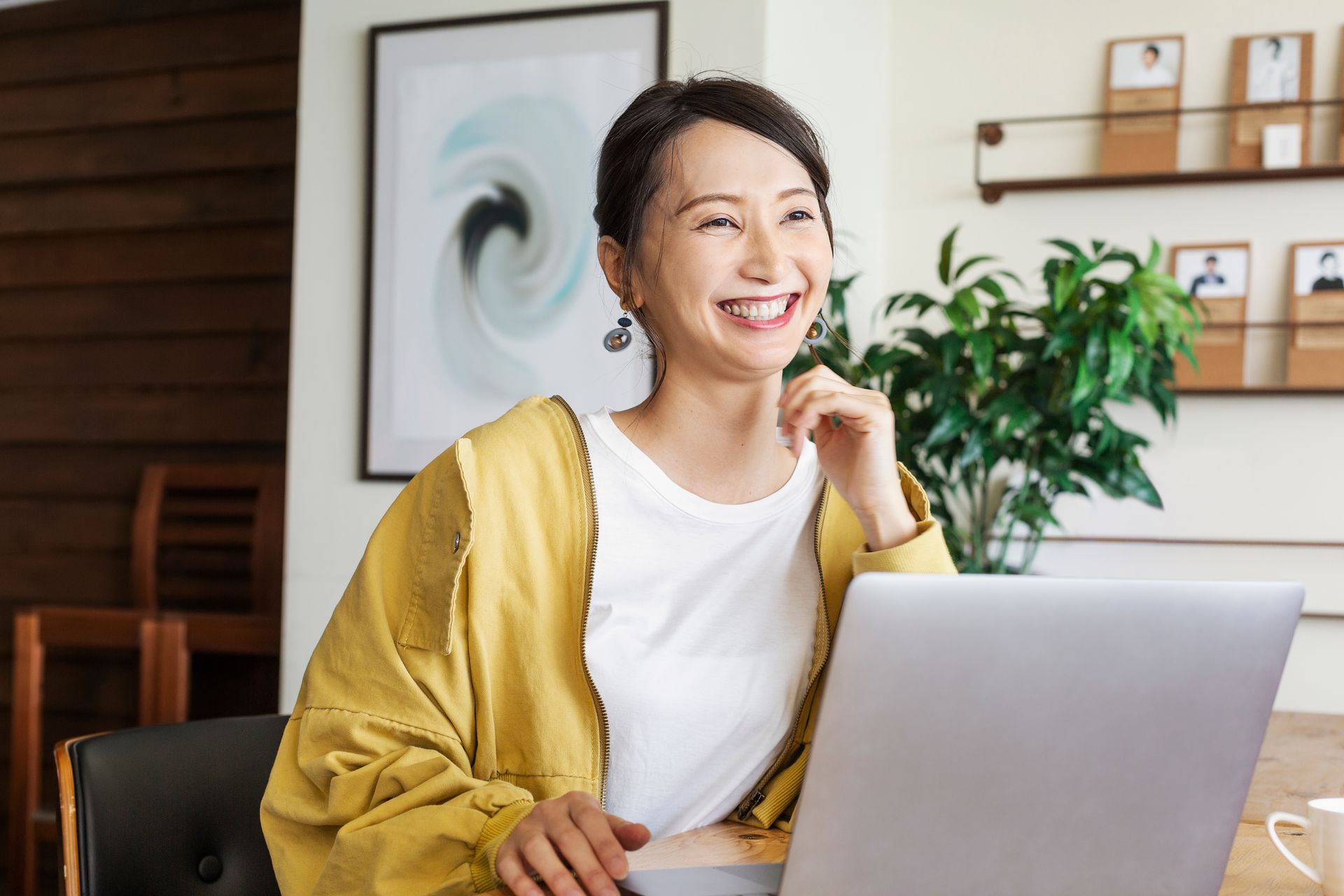 A woman is sitting at a table using a laptop computer.