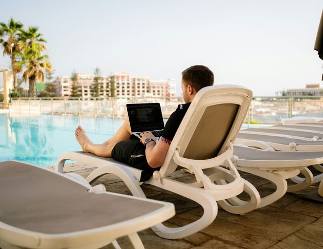 A man is sitting in a lounge chair using a laptop computer.