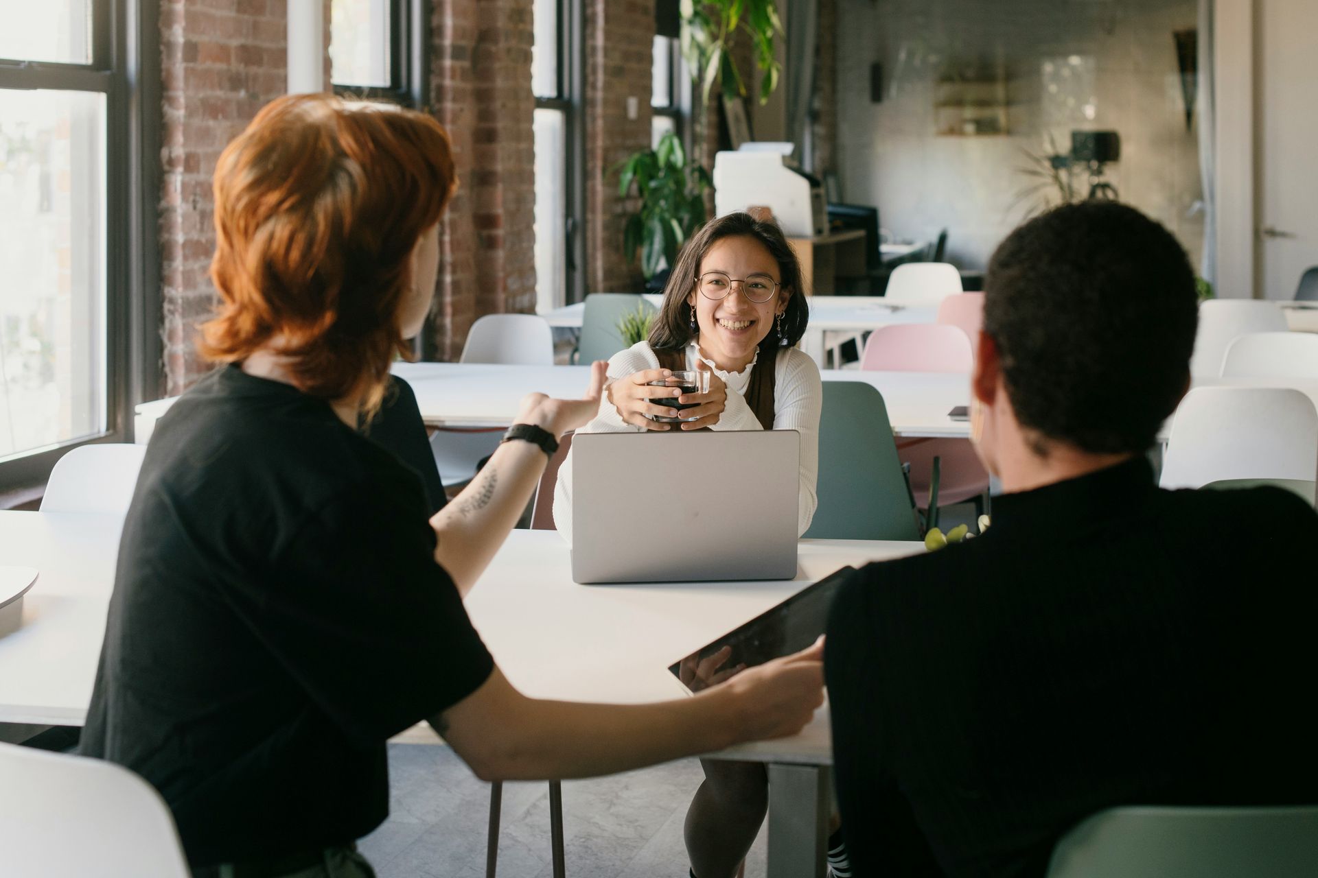 A group of people are sitting at a table with a laptop.