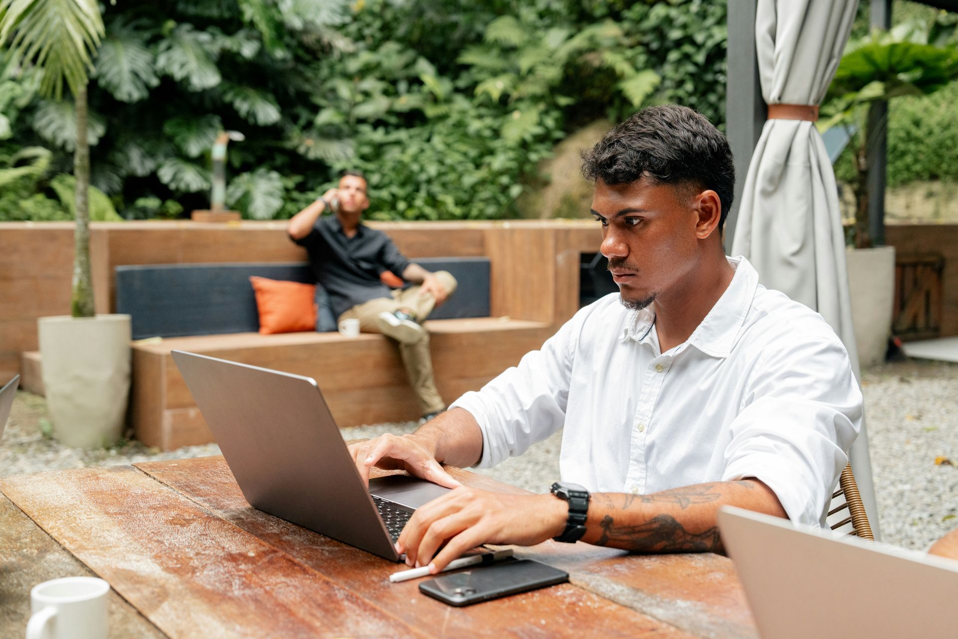 A man is sitting at a table using a laptop computer.