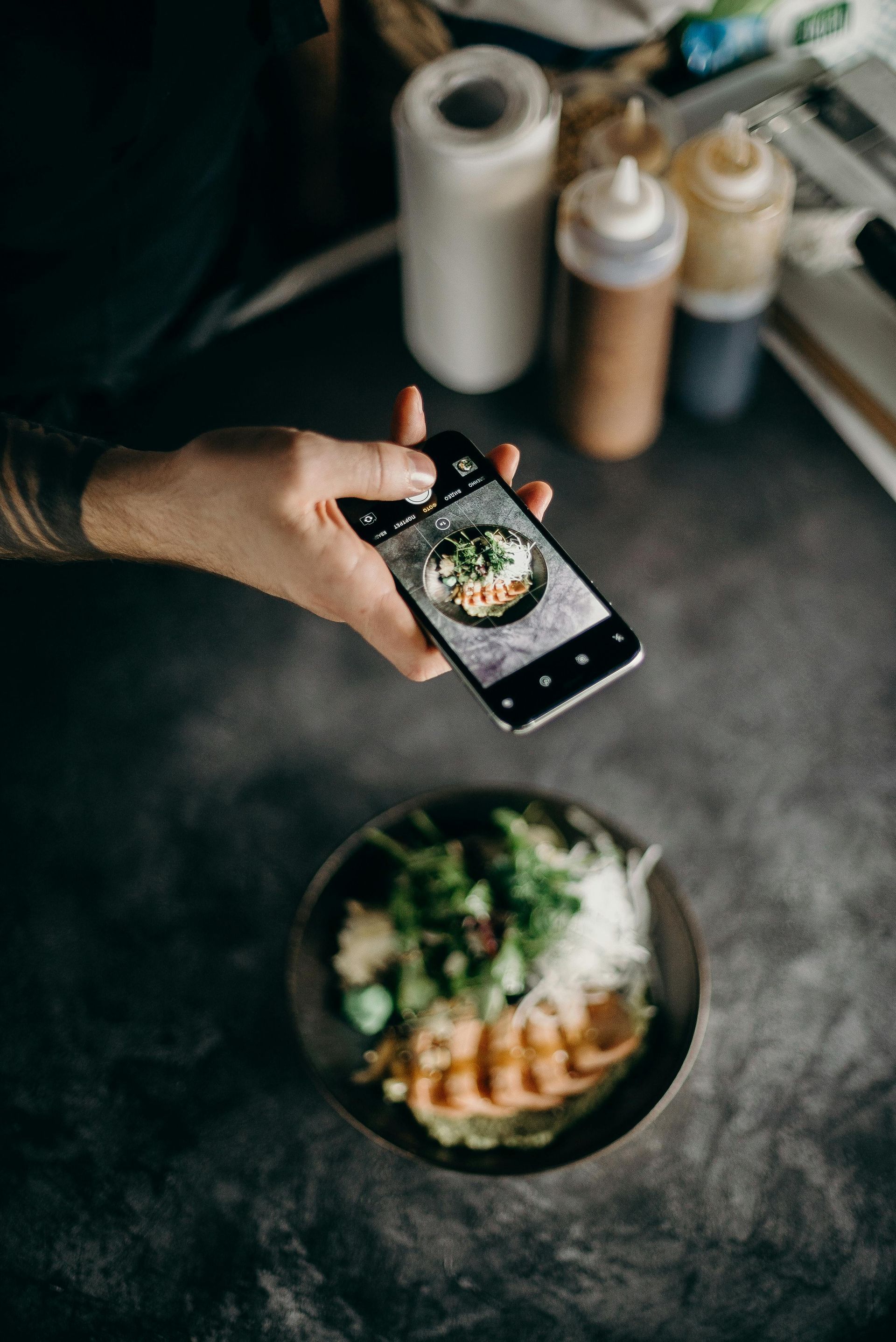 A person is taking a picture of a bowl of food with a cell phone.