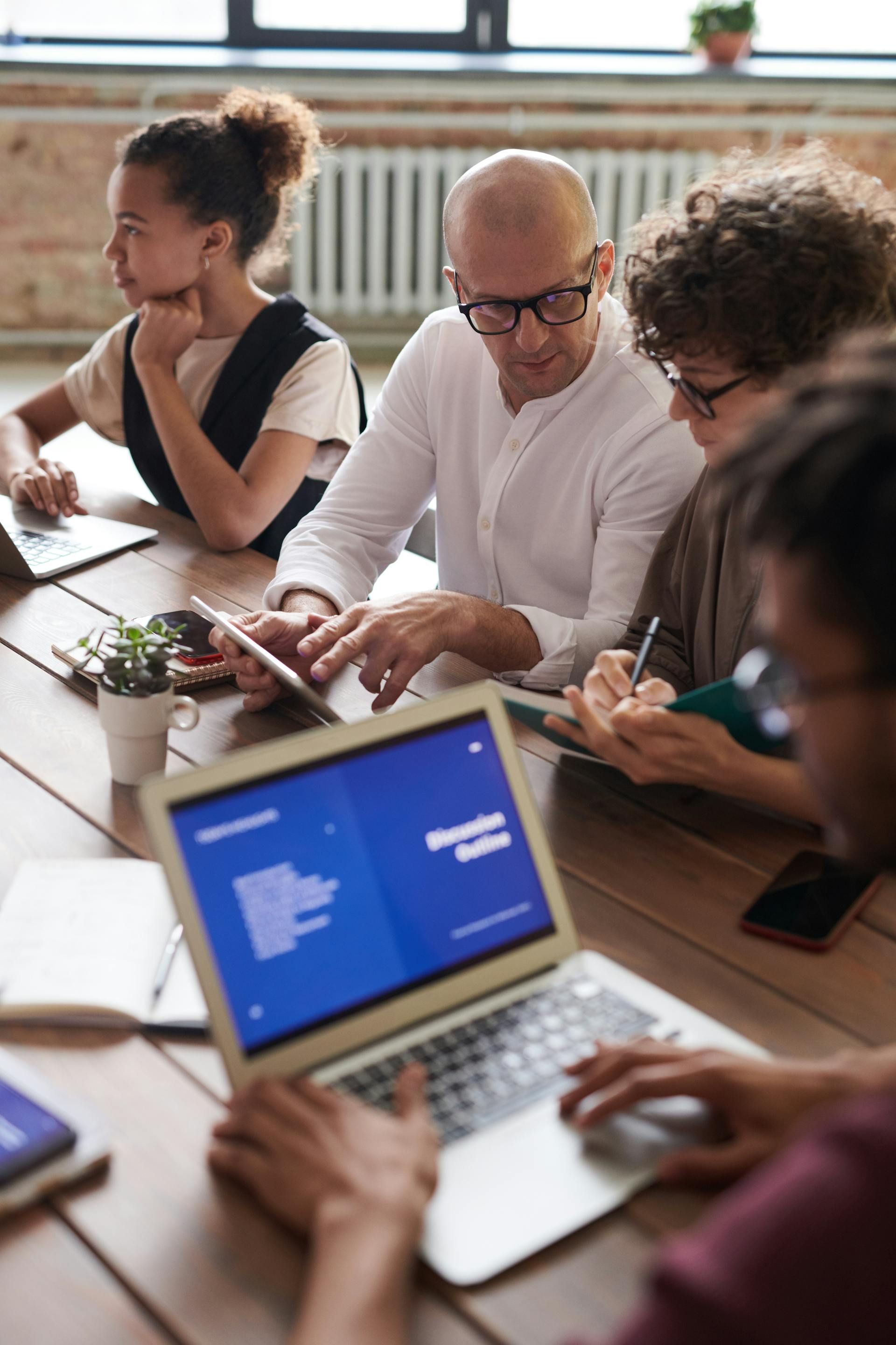 People at a table looking at a laptop and tablet, working together in an office.