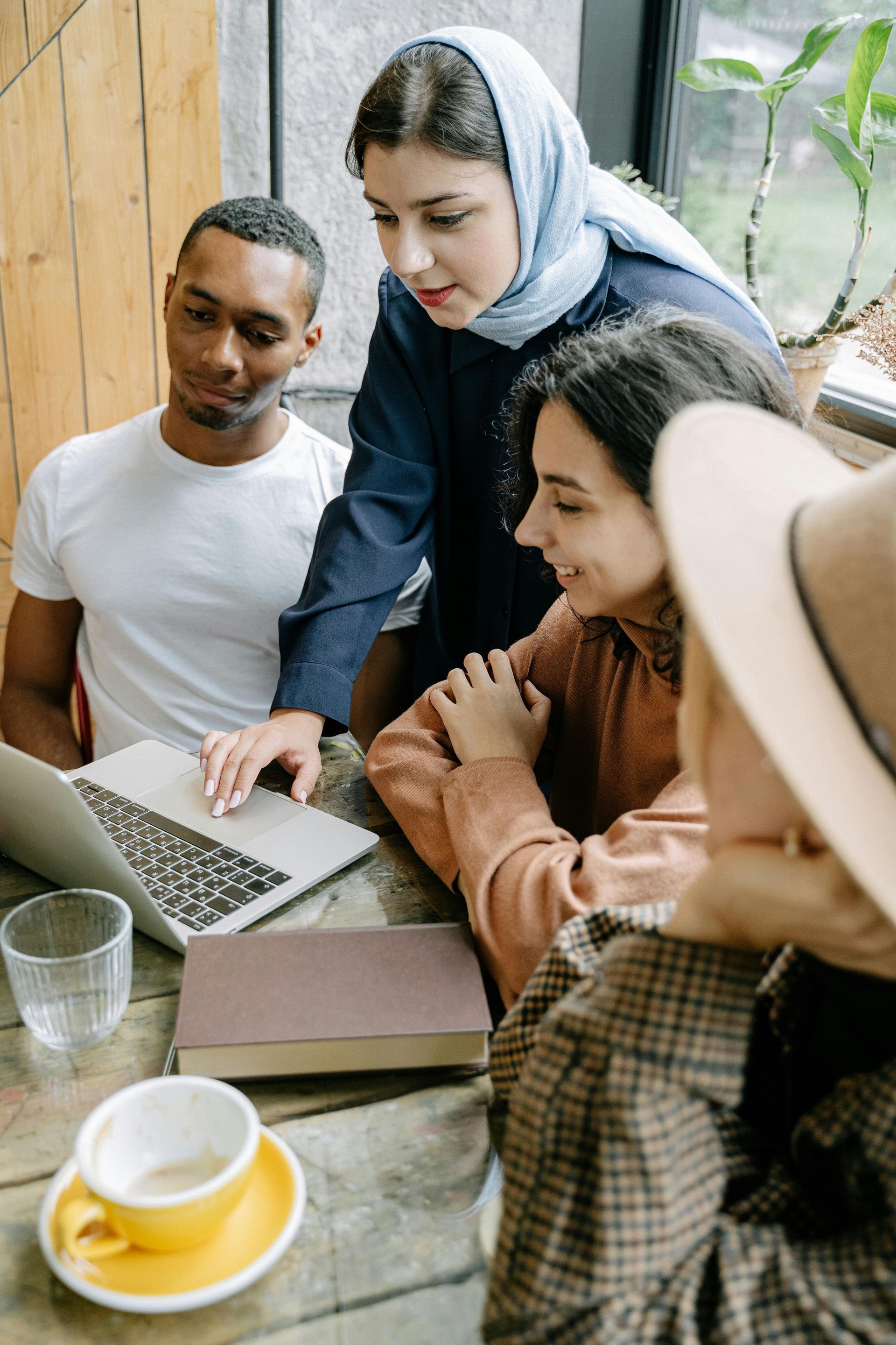 A group of people are sitting at a table looking at a laptop.