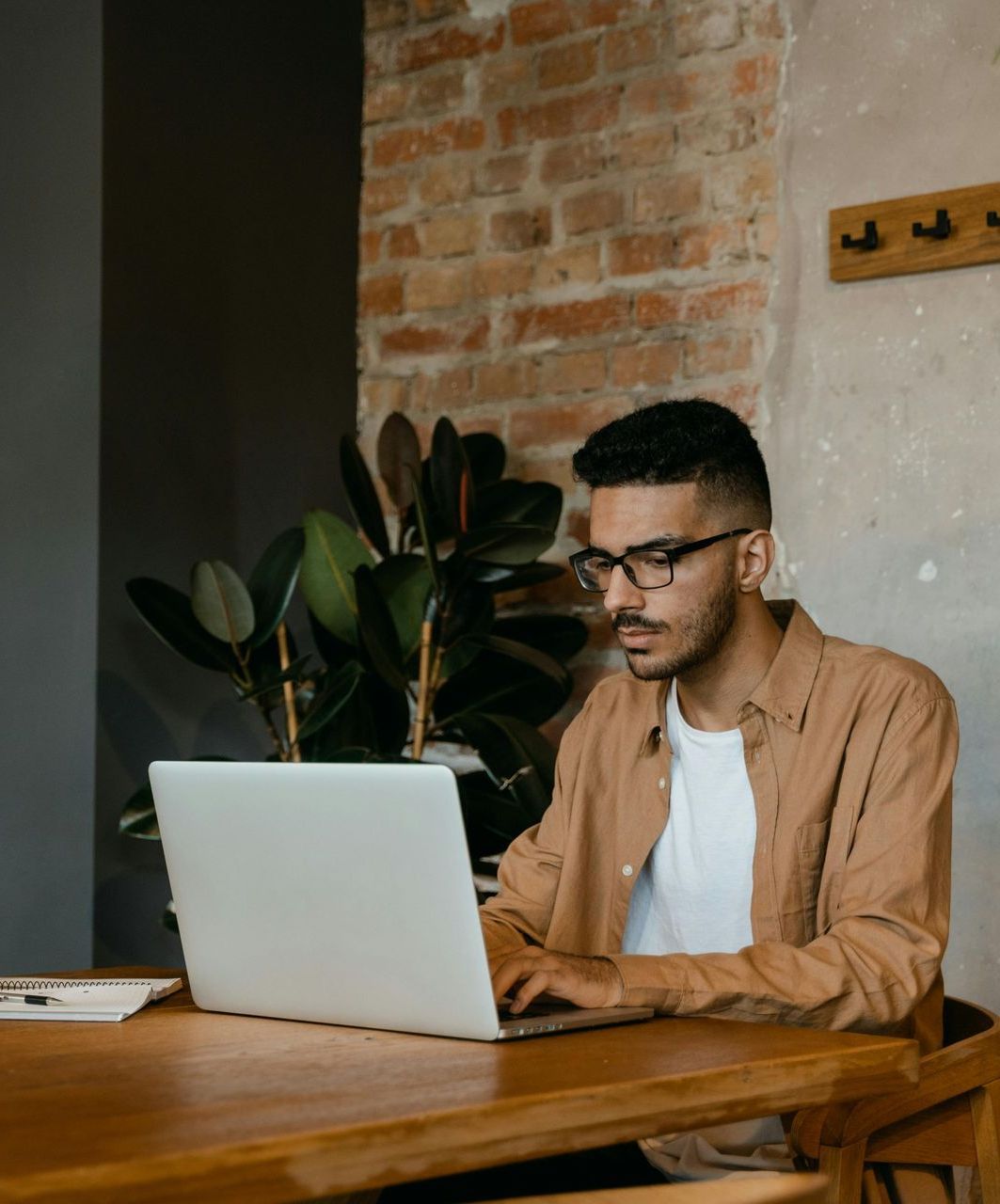 A man is sitting at a table using a laptop computer.