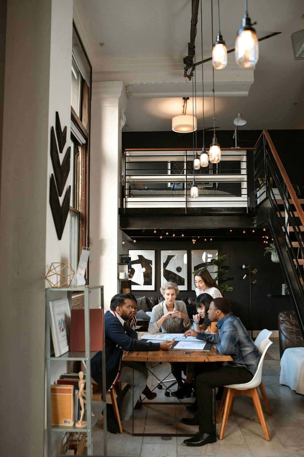 People seated around a wooden table in an office, reviewing documents. White walls, black accent wall.