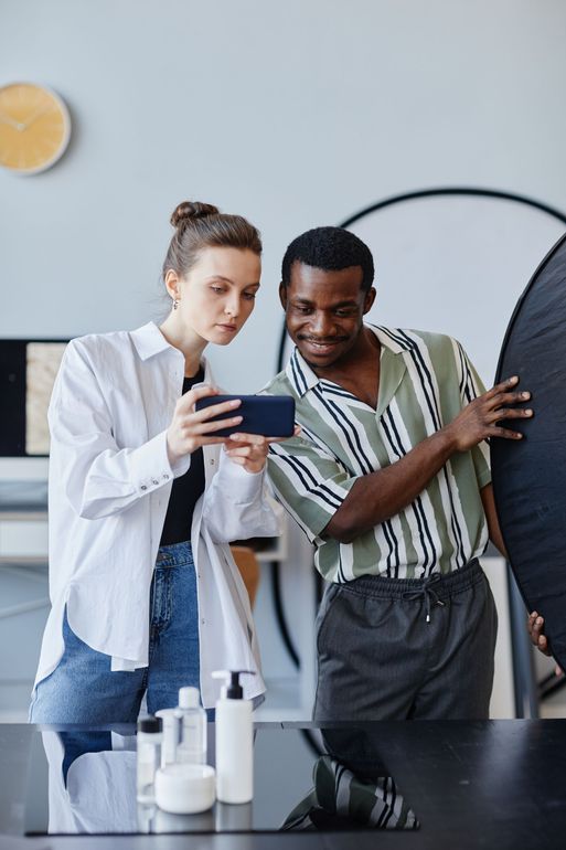 A man and a woman are looking at a cell phone.