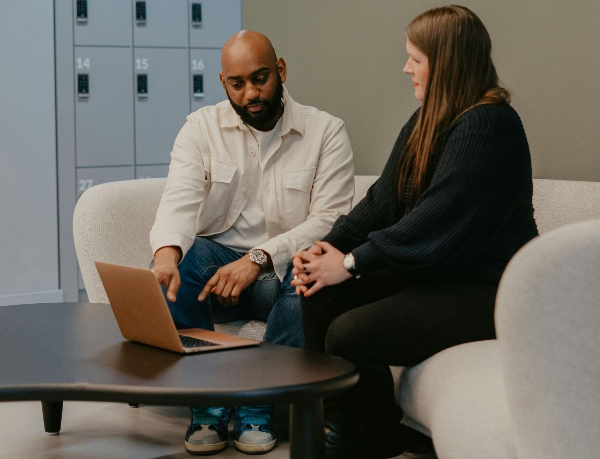 A man and a woman are sitting on a couch looking at a laptop.