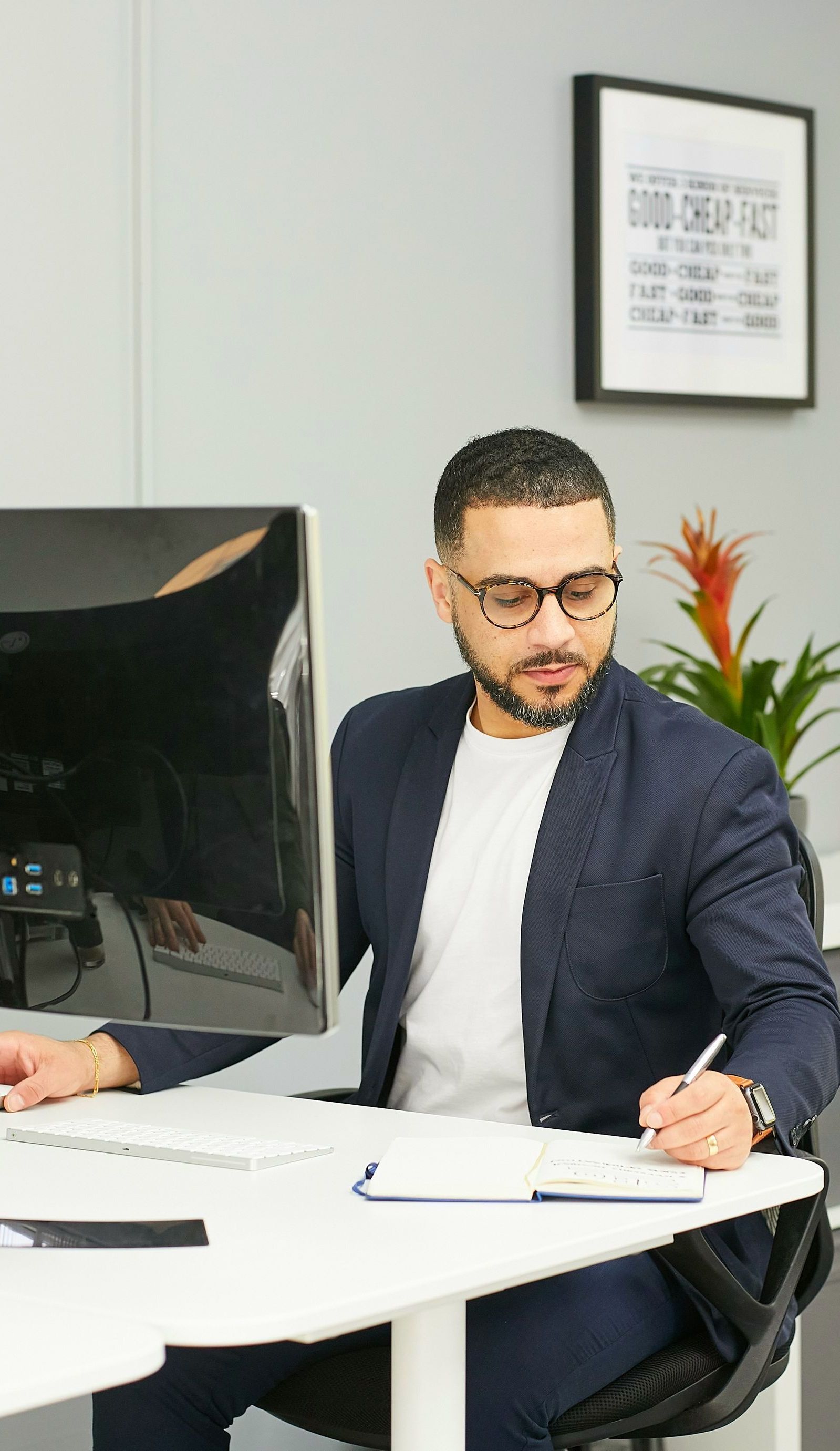 A man in a suit is sitting at a desk in front of a computer.