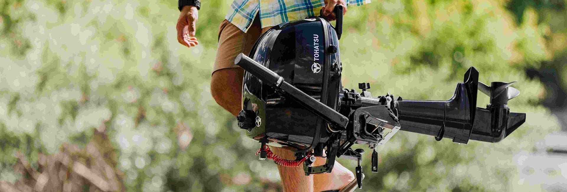 A Person Is Holding A Boat Motor — Cannonvale Marine In Jubilee Pocket, QLD