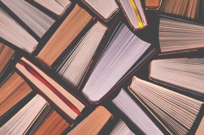 A bunch of books are stacked on top of each other on a table.