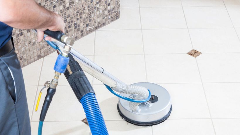 Person cleaning a tile floor with a circular cleaning machine. Person cleaning a tile floor with a circular cleaning machine.