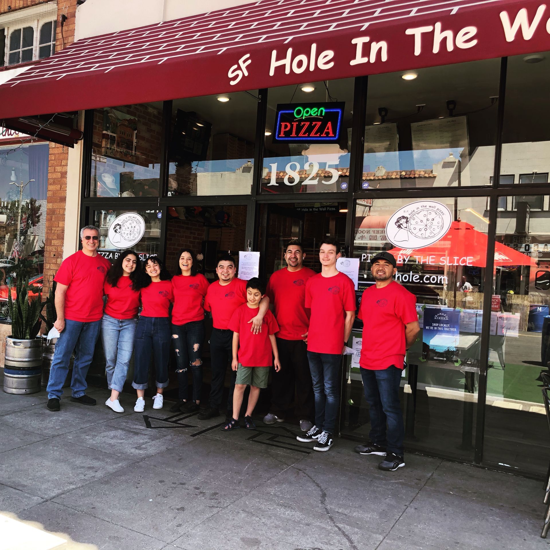 a group of people standing in front of a restaurant called hole in the wall
