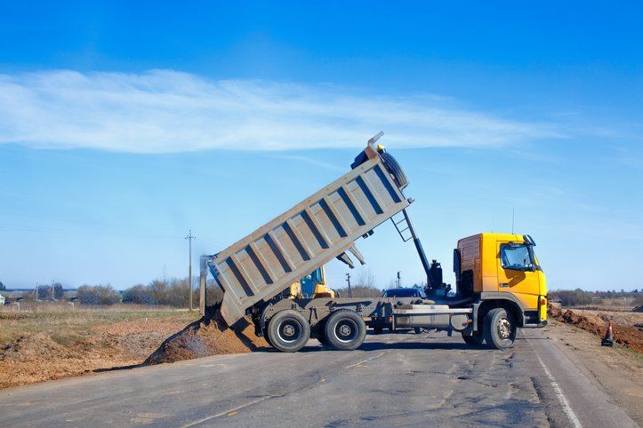 Tipper unloads sand on the road