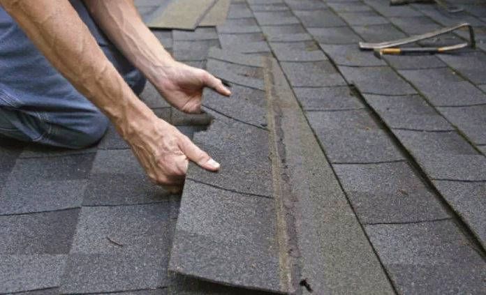 A man is installing shingles on a roof.