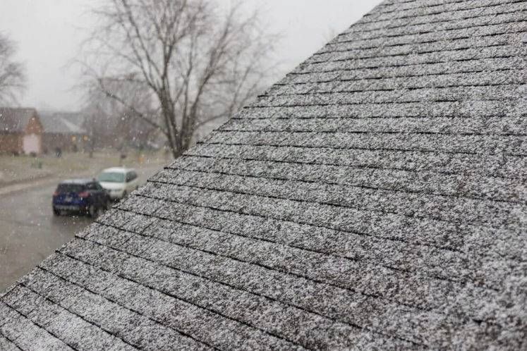 The roof of a house is covered in snow on a cloudy day.