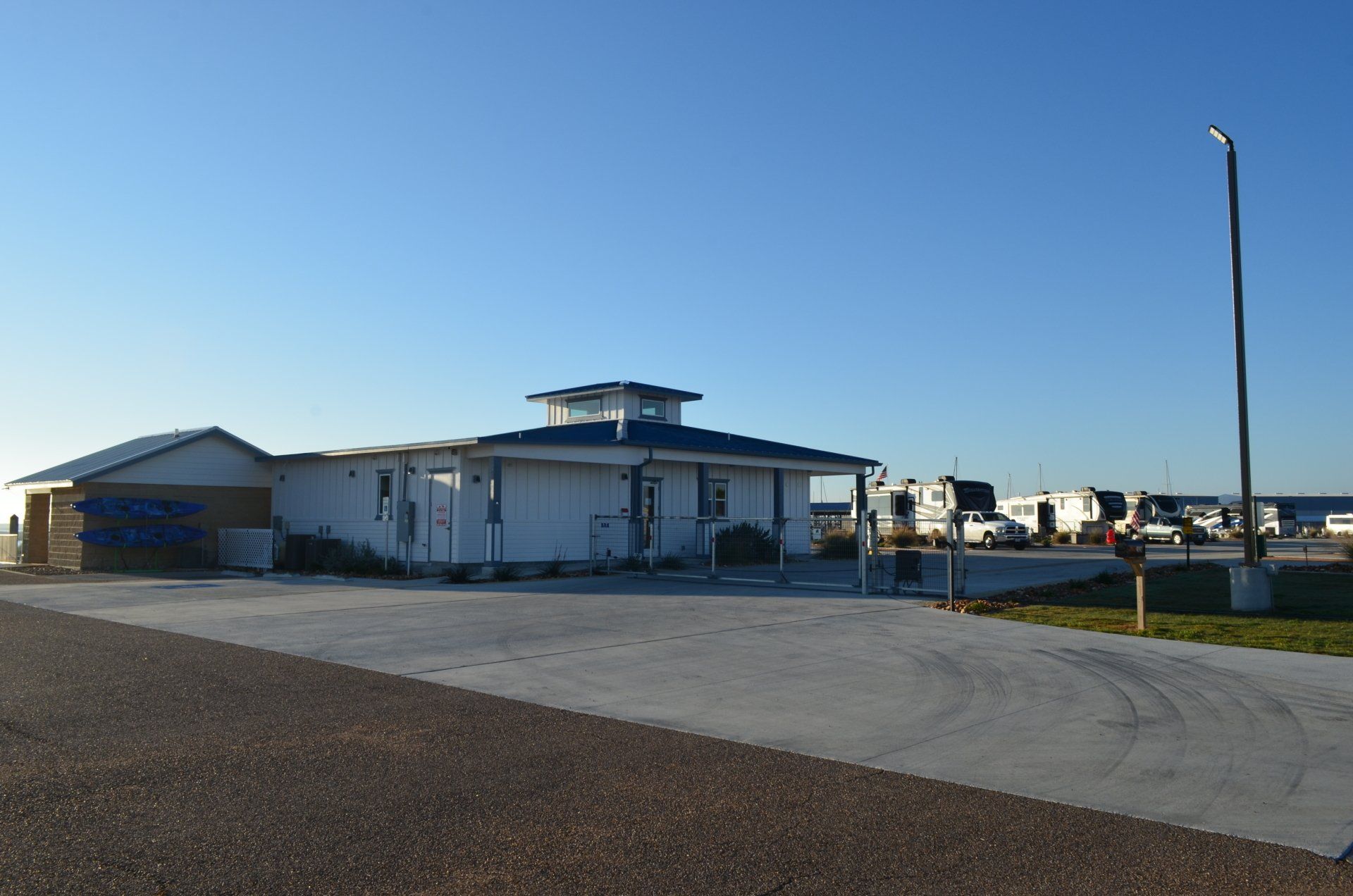 A white house with a blue roof is in a parking lot