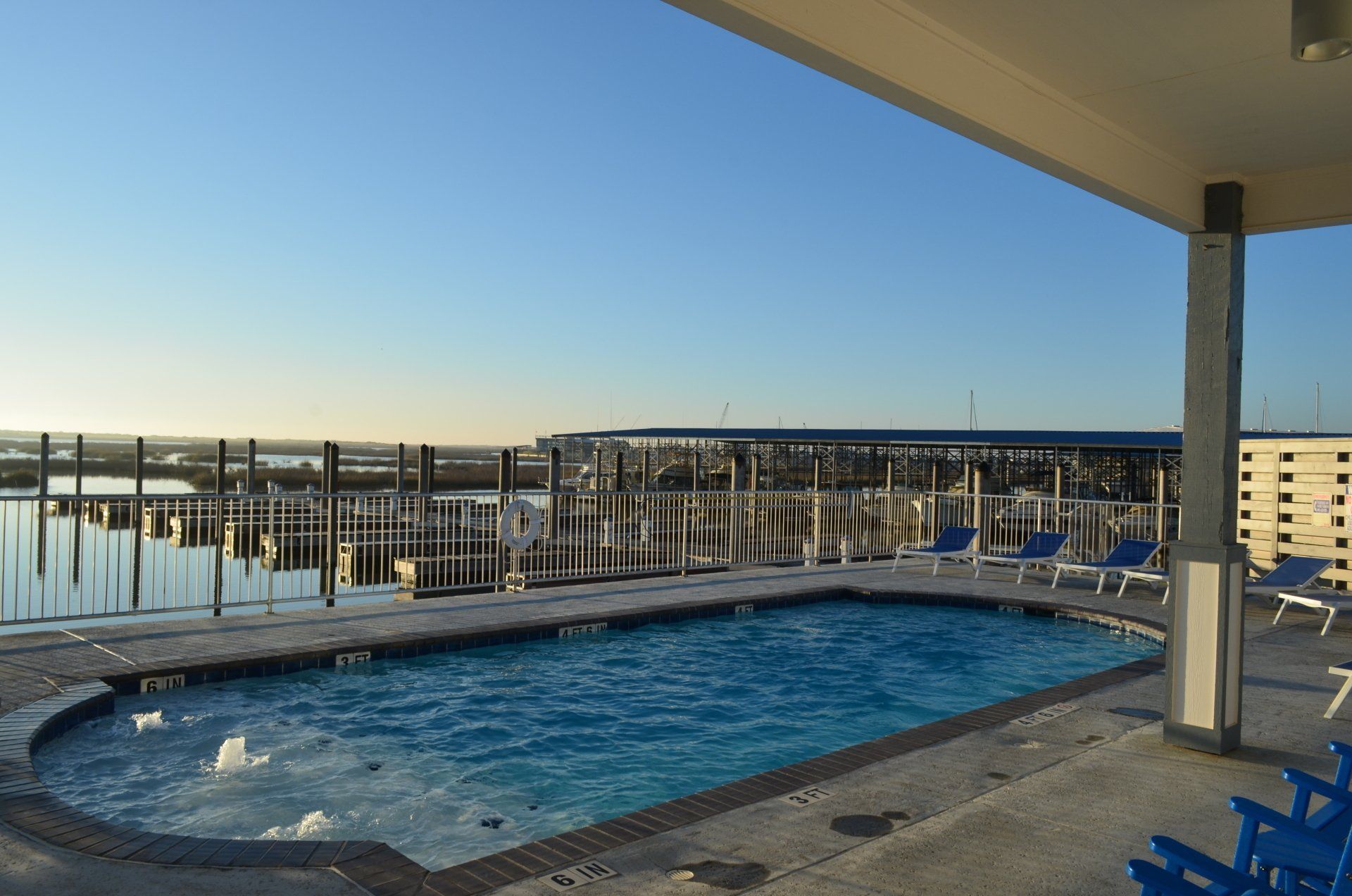 A large swimming pool is surrounded by chairs and a dock.