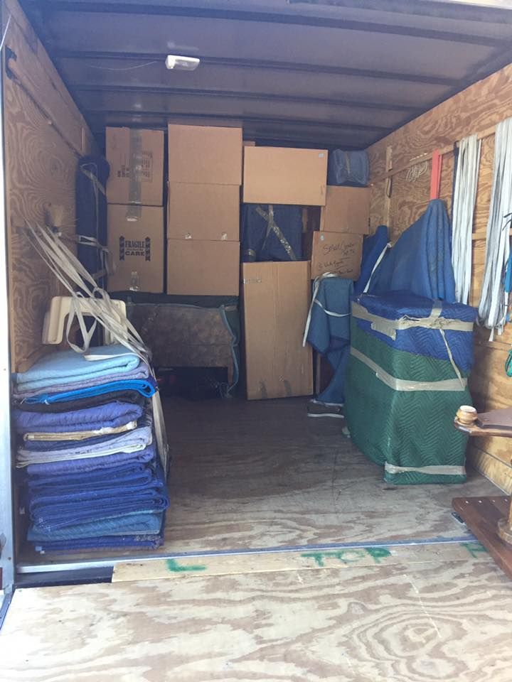 The inside of a moving truck filled with boxes and blankets.