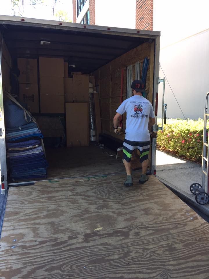 A man is pushing a dolly into a moving truck.