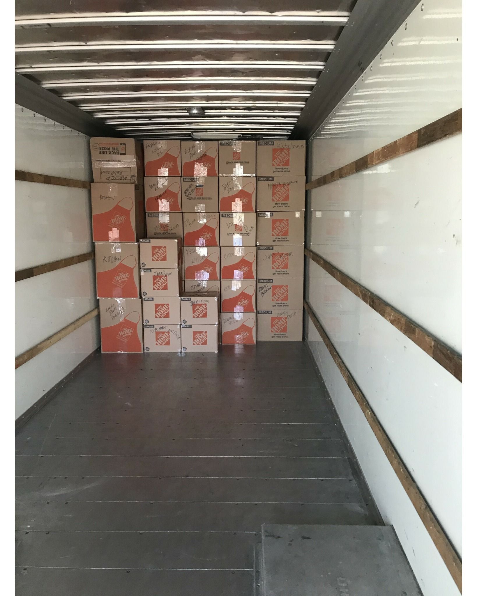 The inside of a moving truck filled with boxes and one of the boxes has the letter g on it
