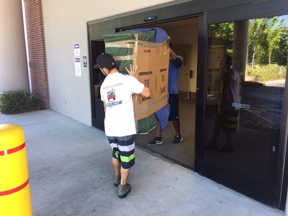 Two men are carrying a large box into a building.