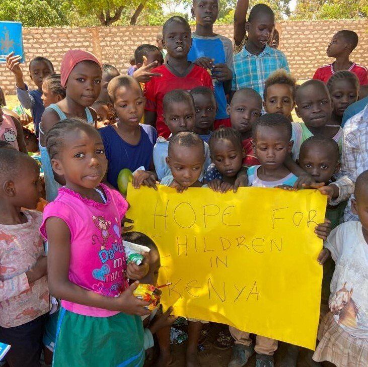 Eine Gruppe von Kindern hält ein Schild mit der Aufschrift „Hoffnung für Kinder in Kenia“