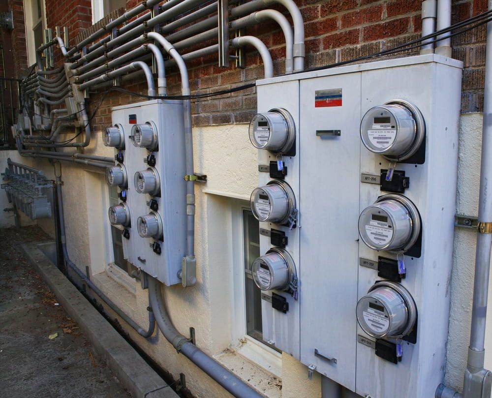 Electric Meters on a Brick Building, With Several Silver Metal Boxes — Darwin Electrical Services in Palmerston, NT