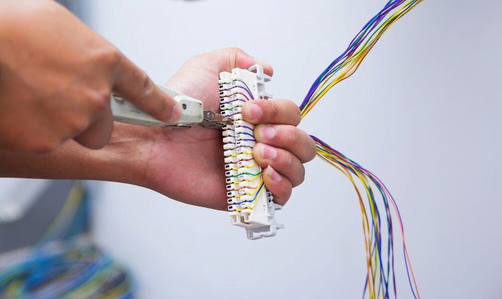 Person Using a Punch-down Tool to Connect Colored Wires to a White Block — Darwin Electrical Services in Humpty Doo, NT