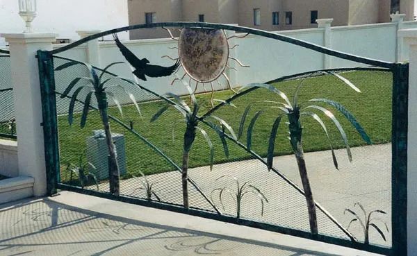 A green gate with a stone wall in the background