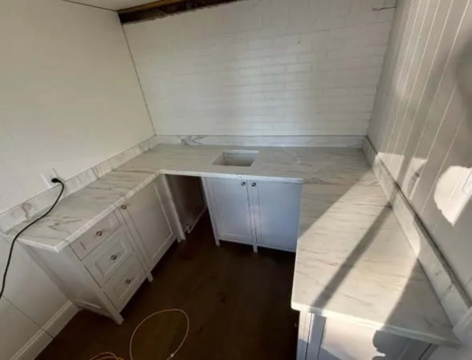 A kitchen with white cabinets and marble counter tops and a sink.
