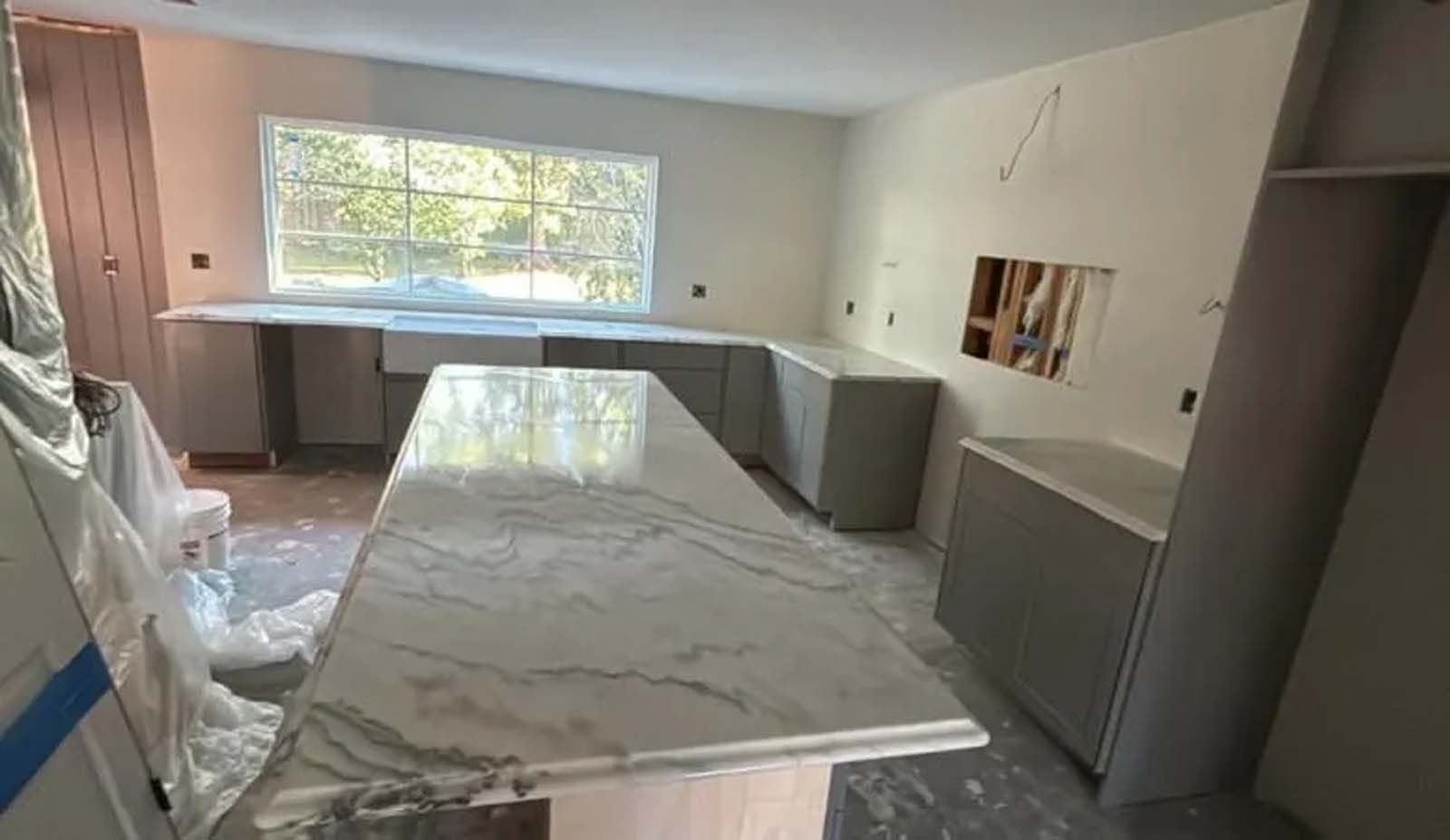A kitchen under construction with a large marble counter top.