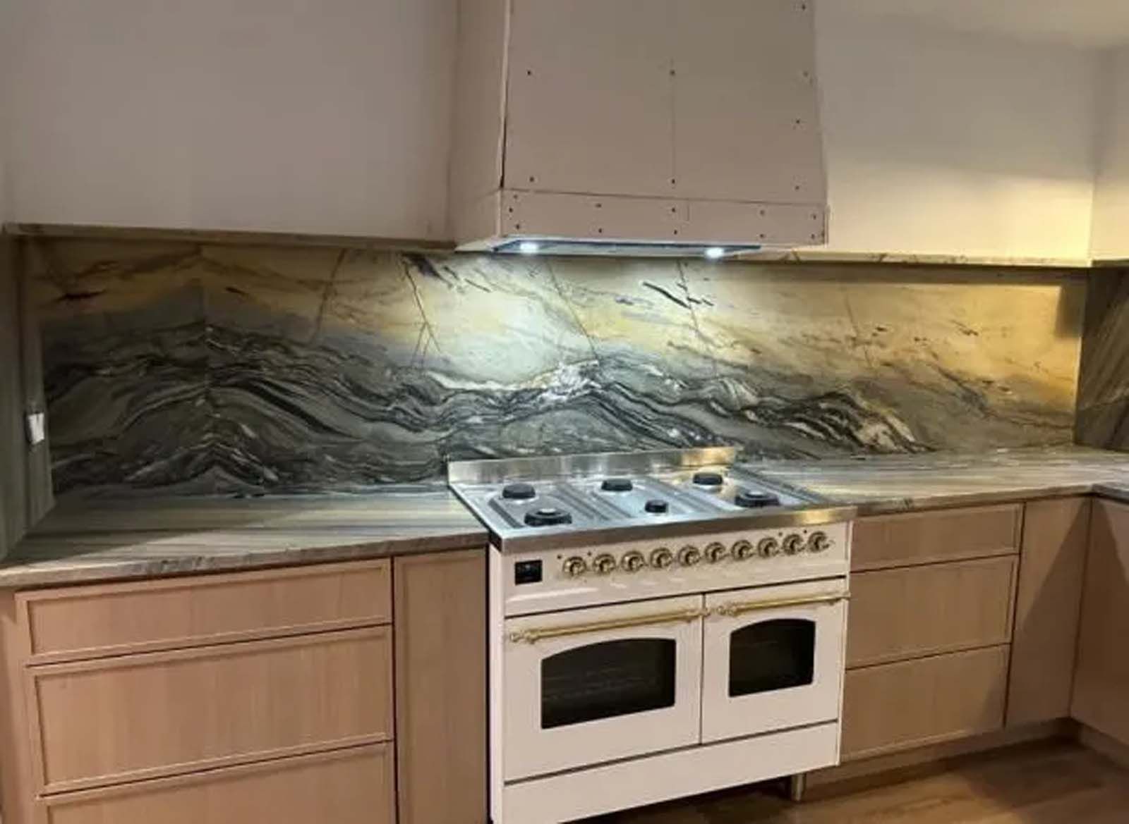 A kitchen with a stove and a marble counter top.