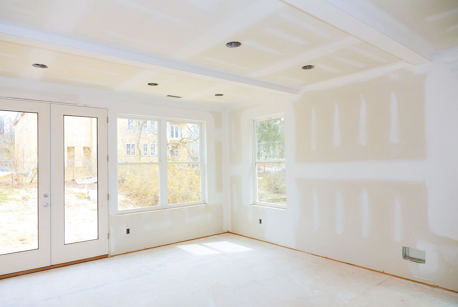 An empty room with a lot of windows and drywall on the walls.