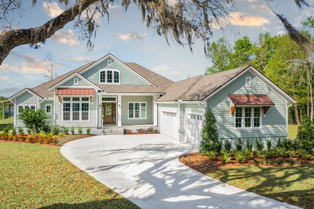 A large house with a driveway leading to it is surrounded by trees and grass.