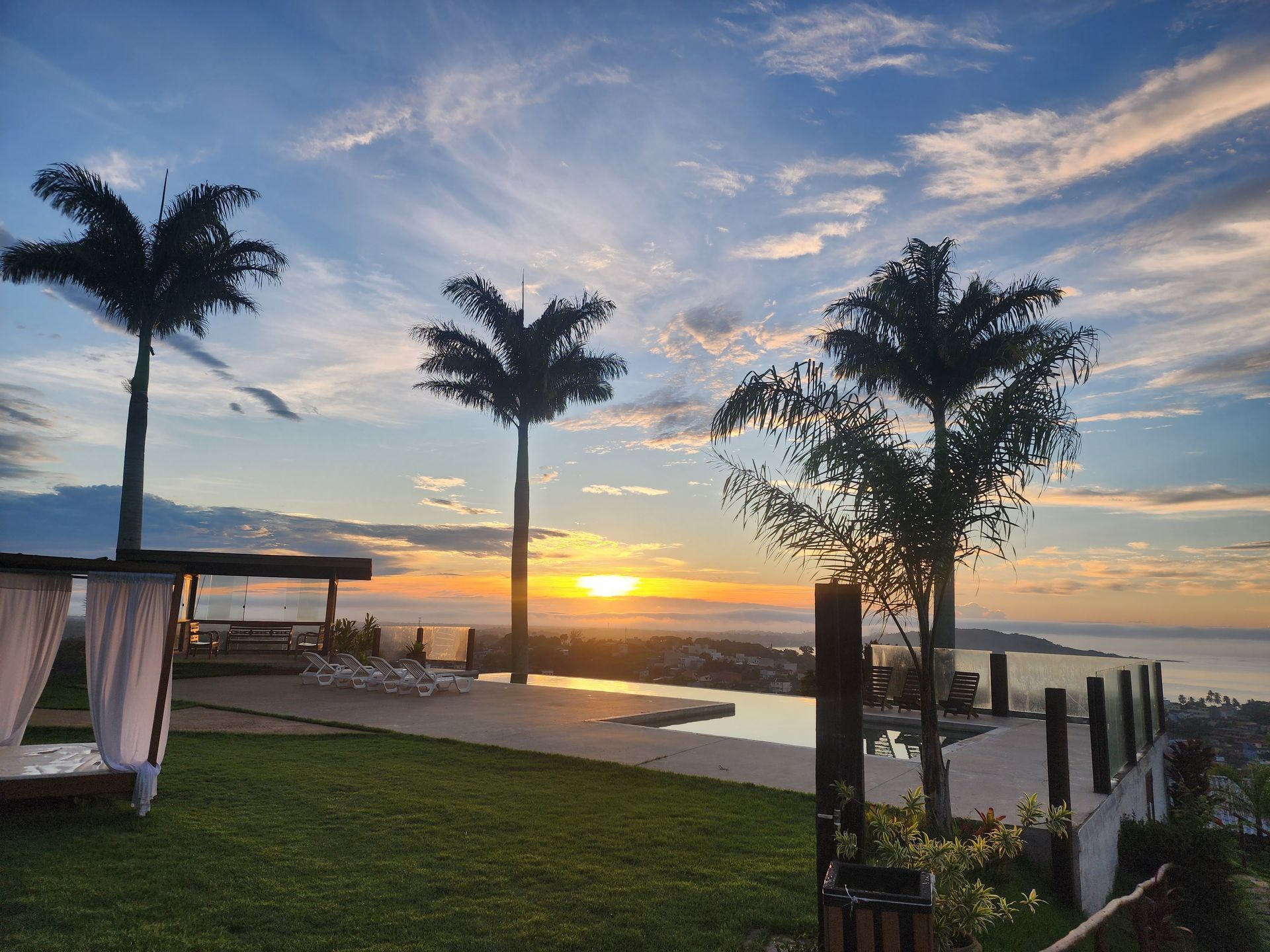 Um pôr do sol sobre o oceano com palmeiras em primeiro plano