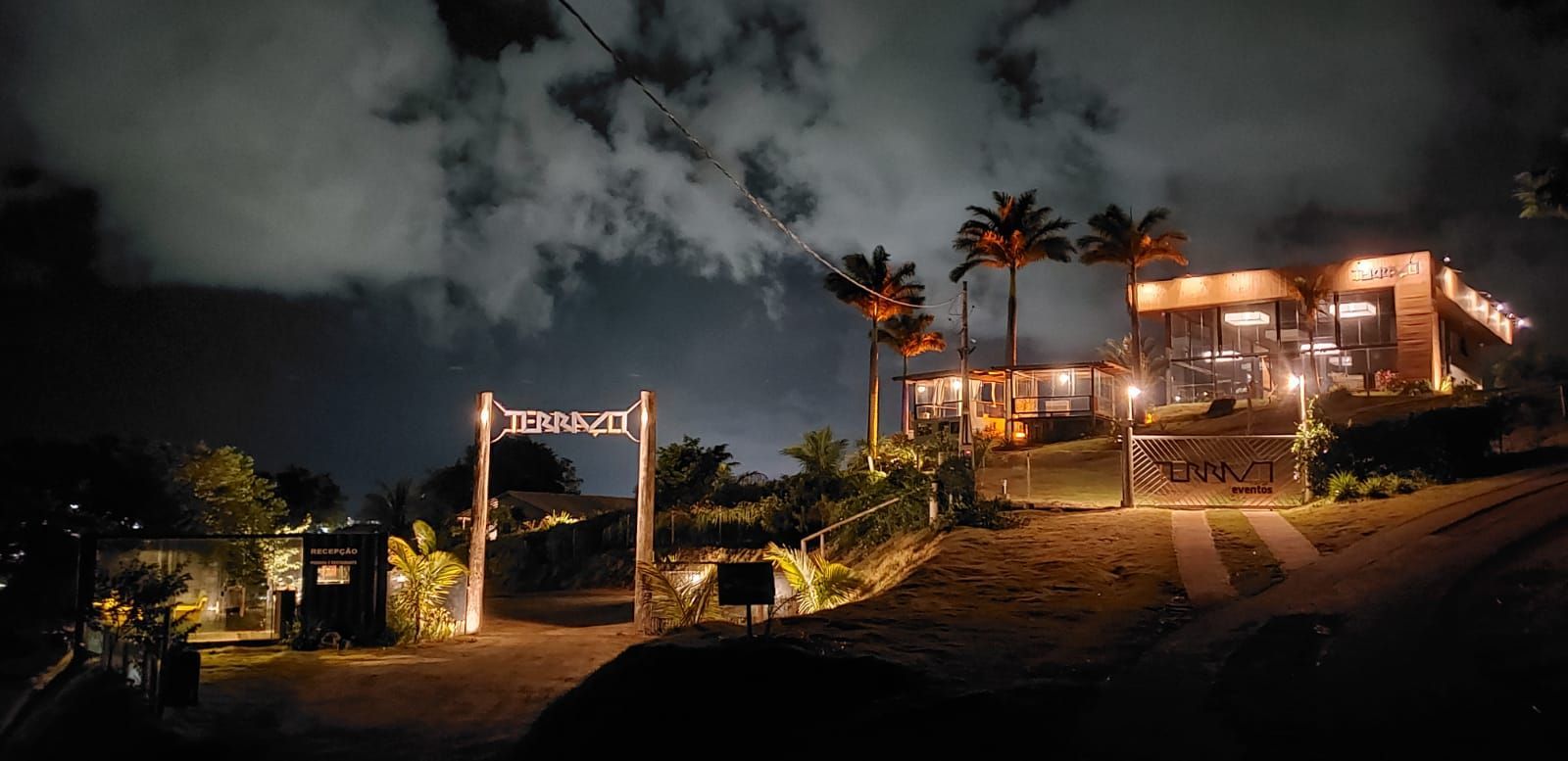 Uma casa iluminada à noite com palmeiras na frente dela.