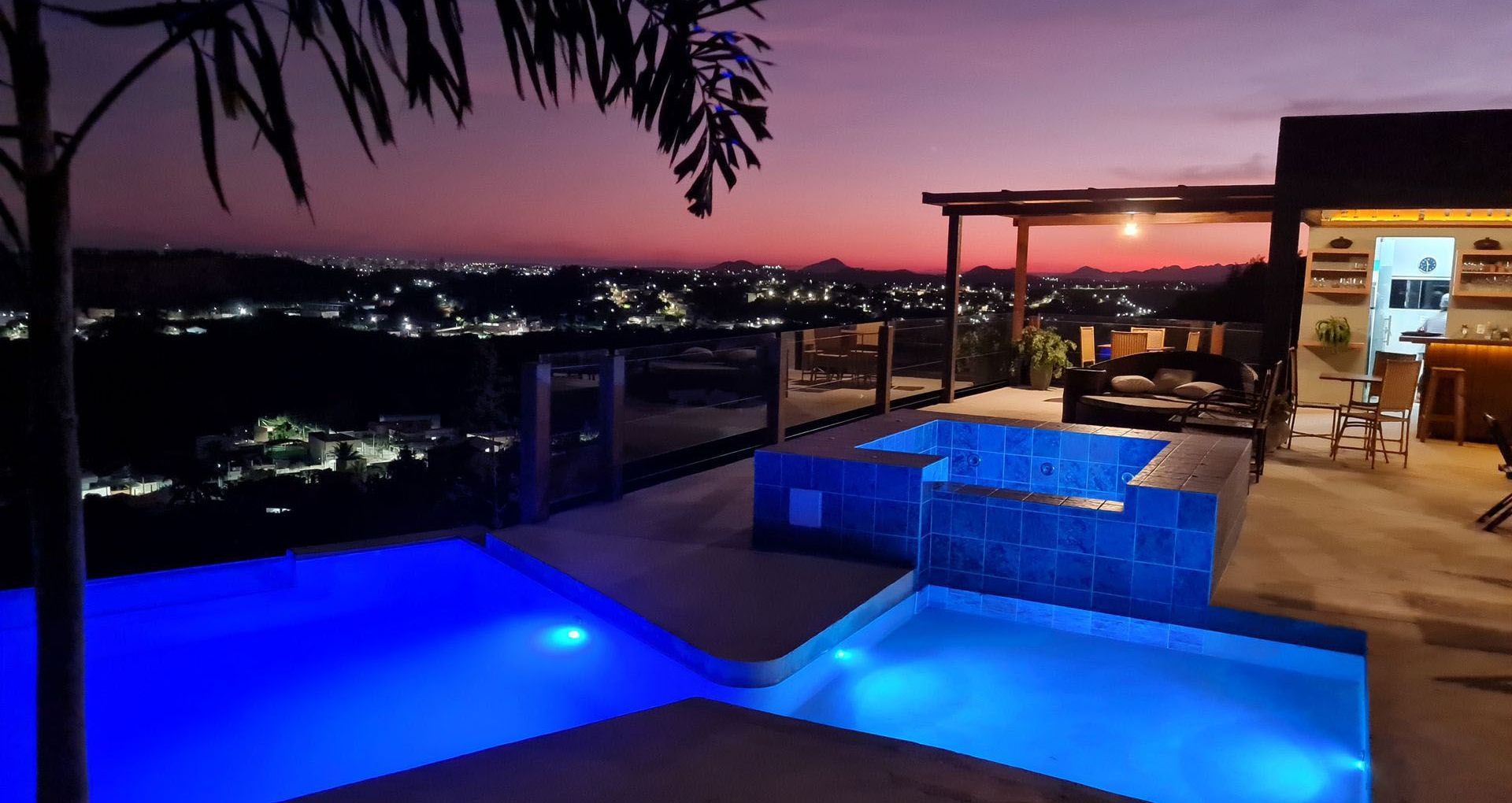 Uma grande piscina com vista para a cidade à noite.
